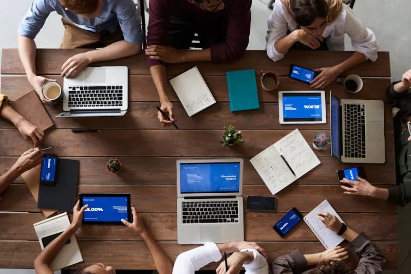 A team gathered around a table of laptops and notebooks